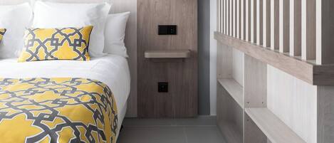 A modern hotel room with a bed, a nightstand, a wall-mounted lamp, and a wooden panel design.