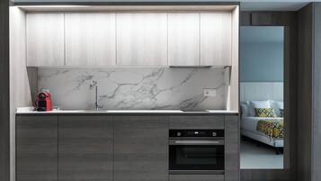 A modern kitchen with a marble backsplash, built-in oven, and grey cabinetry.