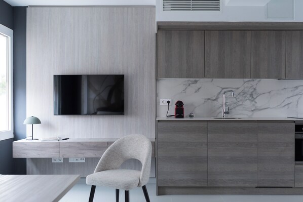 Una cocina moderna con televisor integrado, encimera de mármol y armarios de madera.