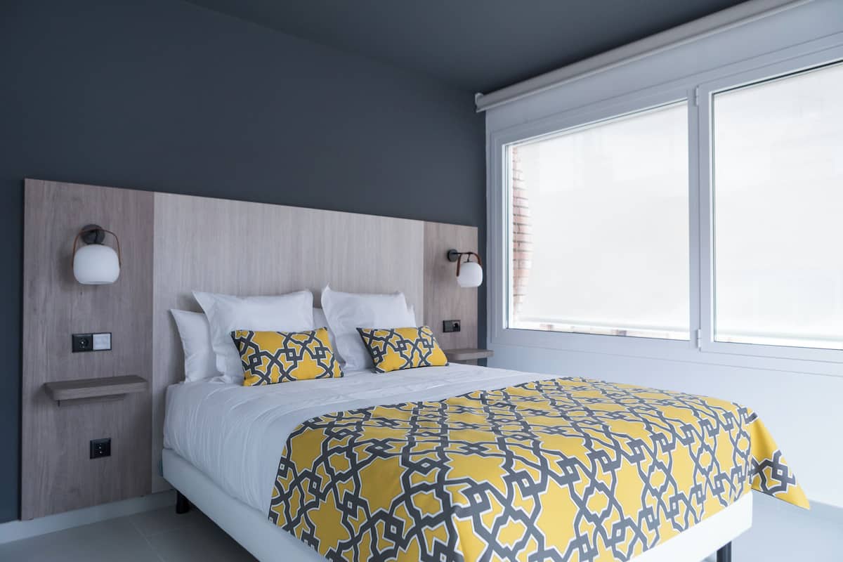 A bedroom with a bed, bedside tables, and wall-mounted lamps.