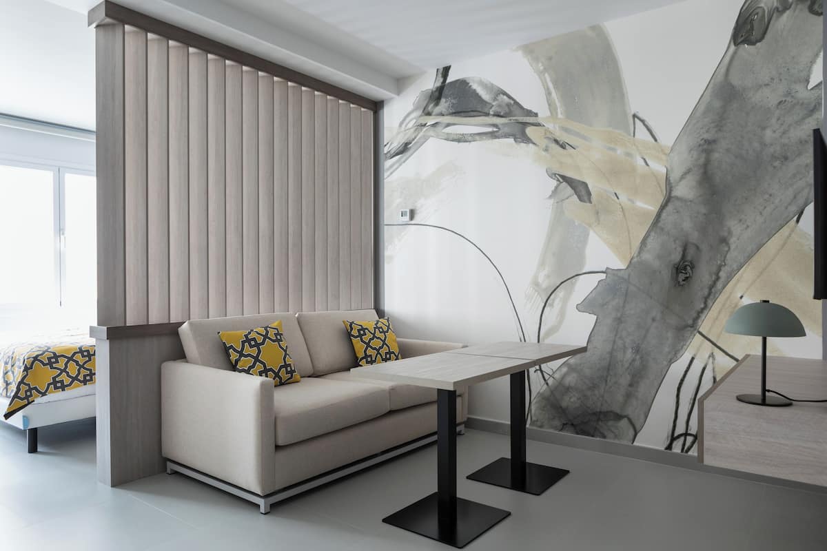 A modern living room with a sofa, a coffee table, and a large abstract painting on the wall.
