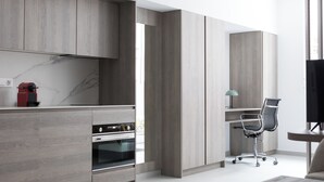 A modern kitchen with wooden cabinets, a built-in oven, and a red coffee machine. - Dobo Madrid Las Torres (Madrid)