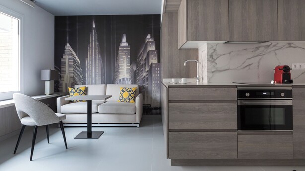 A modern kitchen with a built-in oven and a dining area with a sofa and chairs. - Dobo Madrid Las Torres (Madrid)