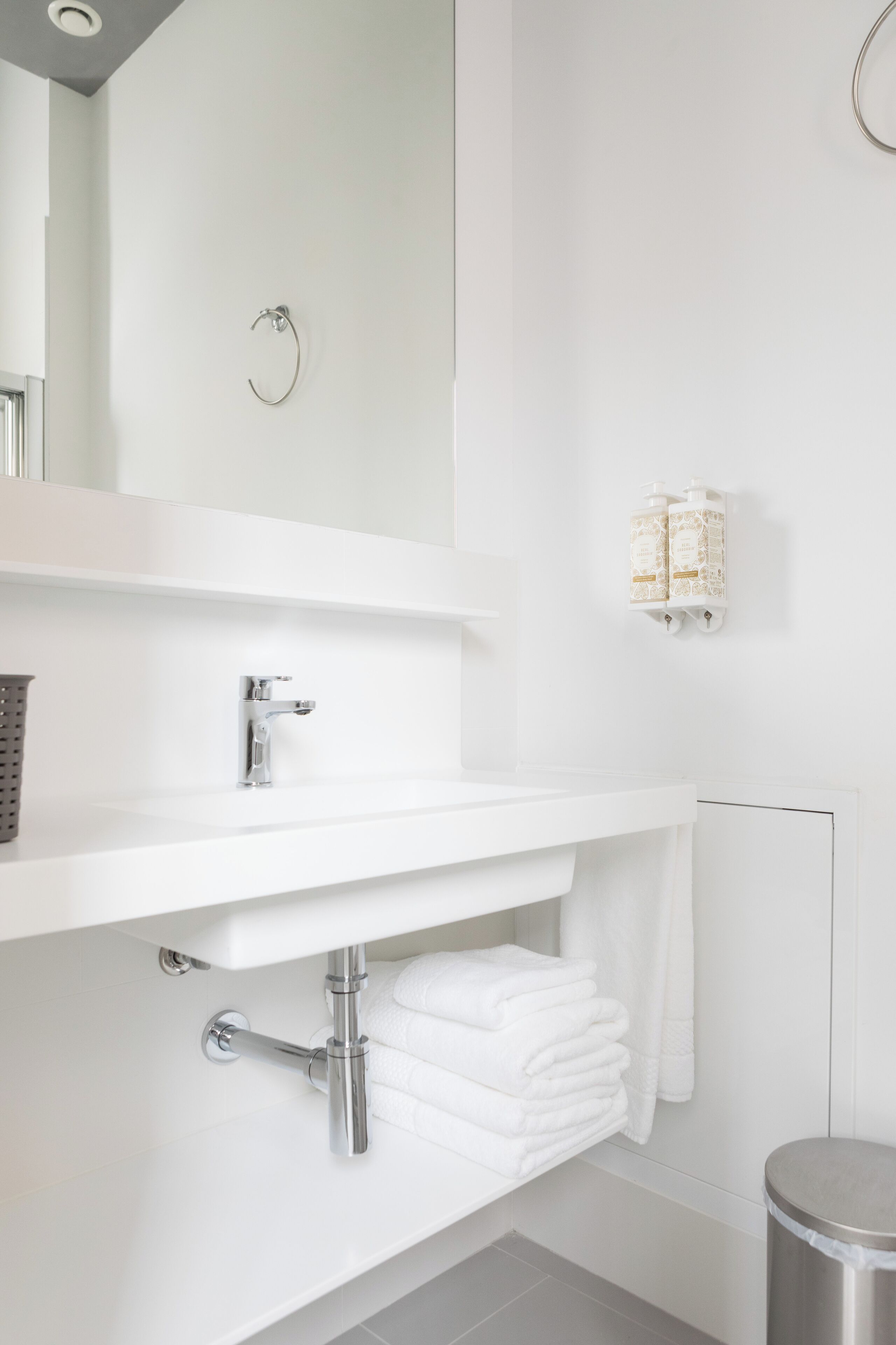 Een moderne badkamer met een witte wastafel, een spiegel en een handdoekrek.