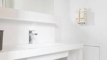 Een moderne badkamer met een witte wastafel, een spiegel en een handdoekrek.
