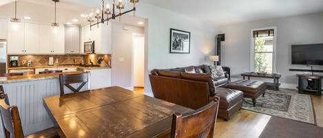 A spacious living area with a dining table, leather sofa, and a flat-screen TV.