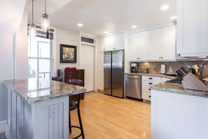 A modern kitchen with white cabinets, stainless steel appliances, and a granite countertop. - Historic Charm in the Heart of Old Town Park City- Walk to Ski, Private Hot Tub (Park City)