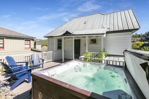 Ein Wohnhaus mit Whirlpool, Gartenmöbeln und einer überdachten Veranda.