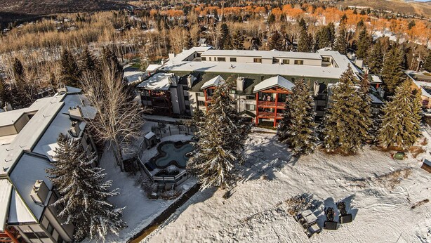 Un resort con un grande edificio, terreno innevato e montagne sullo sfondo.