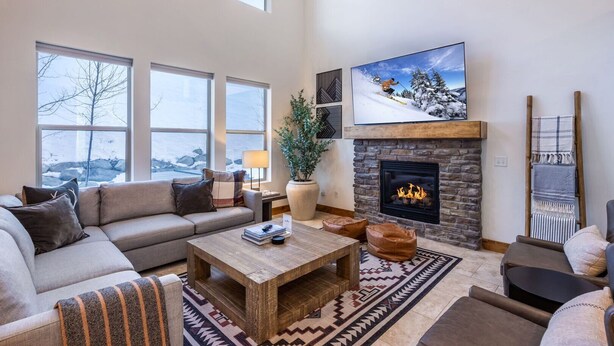 A spacious living room with a fireplace, large windows, and a cozy seating area. - Summer by the Lake! Beautiful Swimming Pool, Patio Hot Tub Firetable BBQ Nature Trails Hiking Biking (Kamas)