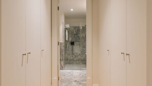 A hallway with a marble floor leading to a bathroom with a shower and a towel rack. - Ando Living - Abrantes 50 House - 202 (Lisbon)