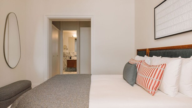 A hotel room with a bed, a chair, a mirror, and a door leading to a bathroom. - Ando Living - Abrantes 50 House - 202 (Lisbon)