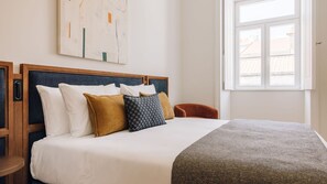 Ein Hotelzimmer mit Bett, Fenster und einem Bild an der Wand.