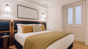 Una camera d'albergo con un letto grande, due comodini, una finestra e illuminazione a parete.