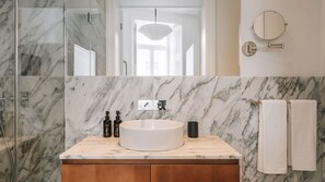 A bathroom with a marble vanity, a sink, and two bottles of shampoo. - Ando Living - Abrantes 50 House - 304 (Lisbon)