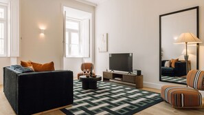 Un salon avec un canapé, un fauteuil, une télévision et un grand miroir.
