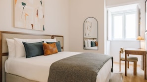 Une chambre d’hôtel bien rangée, avec un lit, un bureau et une chaise.