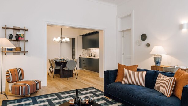 Un salon moderne avec un canapé bleu, des coussins à rayures et un tapis à motifs.