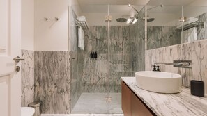 Un baño moderno con un espejo grande, un lavabo redondo y una zona de ducha.