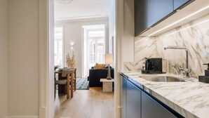 A modern kitchen with a marble countertop, a built-in sink, and a coffee machine. - Ando Living - Abrantes 50 House - 301 (Lisbon)