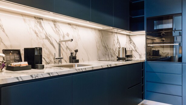 A modern kitchen with a marble backsplash, stainless steel appliances, and dark blue cabinetry. - Ando Living - Abrantes 50 House - 301 (Lisbon)
