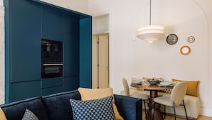 Una sala de estar moderna con un aparador azul, una mesa de comedor con sillas y una lámpara colgante.