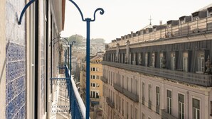 A view of a cityscape with buildings of varying heights and architectural styles, including a prominent building with a balcony and a sign that reads "Casa de Deposito". - Ando Living - Abrantes 50 House - 401 (Lisbon)