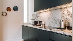 A modern kitchen with dark cabinets, a marble countertop, and a built-in stove. - Ando Living - Abrantes 50 House - 506 (Lisbon)