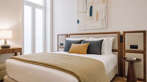 Ein Hotelzimmer mit einem großen Bett, einem Nachttisch mit Lampe, einem kleinen runden Tisch und einer Wandbedienung.