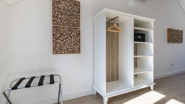 Una habitación moderna con un armario blanco, suelo de madera y decoración en la pared.
