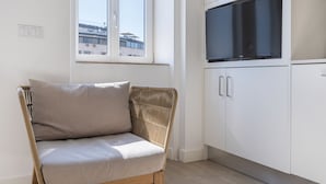 A modern living room with a wicker sofa, a flat-screen TV, and white cabinetry. - Garcia 28 Apartment 3A (Lisbon)