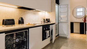 A modern kitchen with a dishwasher, oven, and a coffee maker on the counter. - Ando Living - Corpo Santo House - 203 (Lisbon)