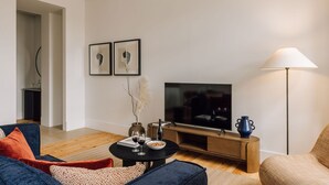 A modern living room with a TV, sofa, coffee table, and a lamp. - Ando Living - Corpo Santo House - 301 (Lisbon)