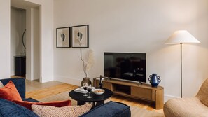 A modern living room with a TV, sofa, coffee table, and a lamp. - Ando Living - Corpo Santo House - 301 (Lisbon)