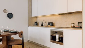 A modern kitchen with white cabinets, a built-in oven, and a coffee machine. - Ando Living - Corpo Santo House - 301 (Lisbon)