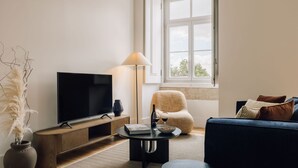 Una sala de estar moderna con un televisor de pantalla plana, una mesa de centro, un sofá y una silla.