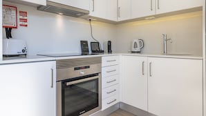 Una cucina moderna con mobili bianchi, un forno in acciaio inossidabile, una macchina da caffè e un tostapane.