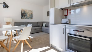Una cucina moderna con forno a incasso e tostapane. C'è un'area pranzo con un tavolo e sedie bianche.