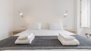 Een hotelkamer met een groot bed, twee nachtkastjes en twee wandlampen.