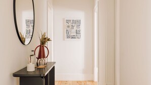 Un couloir avec une console en bois foncé, un miroir et une œuvre d’art encadrée accrochée au mur.