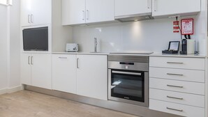 Egy modern konyha fehér szekrényekkel, egy Bosch sütővel, egy kenyérpirítóval és egy síkképernyős televízióval.