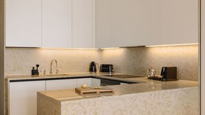 A modern kitchen with a marble countertop, a built-in sink, and stainless steel appliances. - Ando Living - Corpo Santo House - 101 (Lisbon)