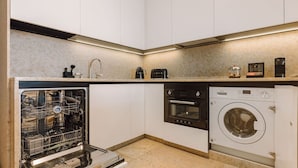A compact kitchen with a dishwasher, oven, and washing machine. - Ando Living - Corpo Santo House - 101 (Lisbon)