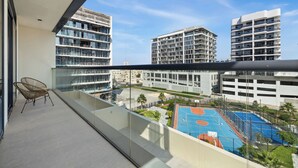 Un balcon avec vue sur des immeubles modernes et un terrain de basket.