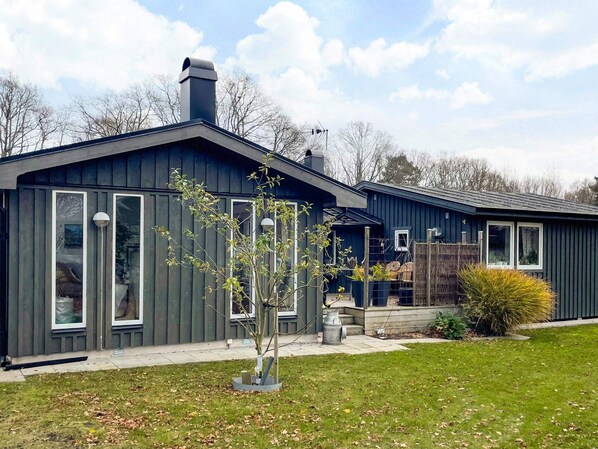 Une maison à deux étages, à l’extérieur sombre, dotée de grandes fenêtres et d’une cheminée.