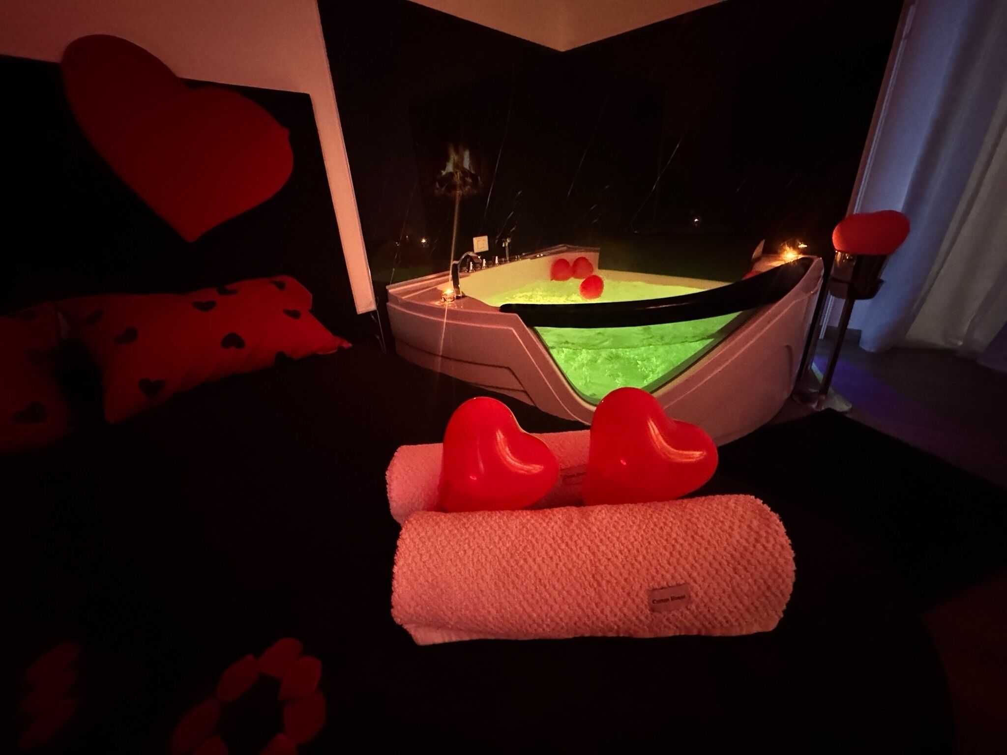 Ein gemütliches Zimmer mit einer Badewanne, einem herzförmigen Kopfkissen und einem Kissen auf dem Boden.