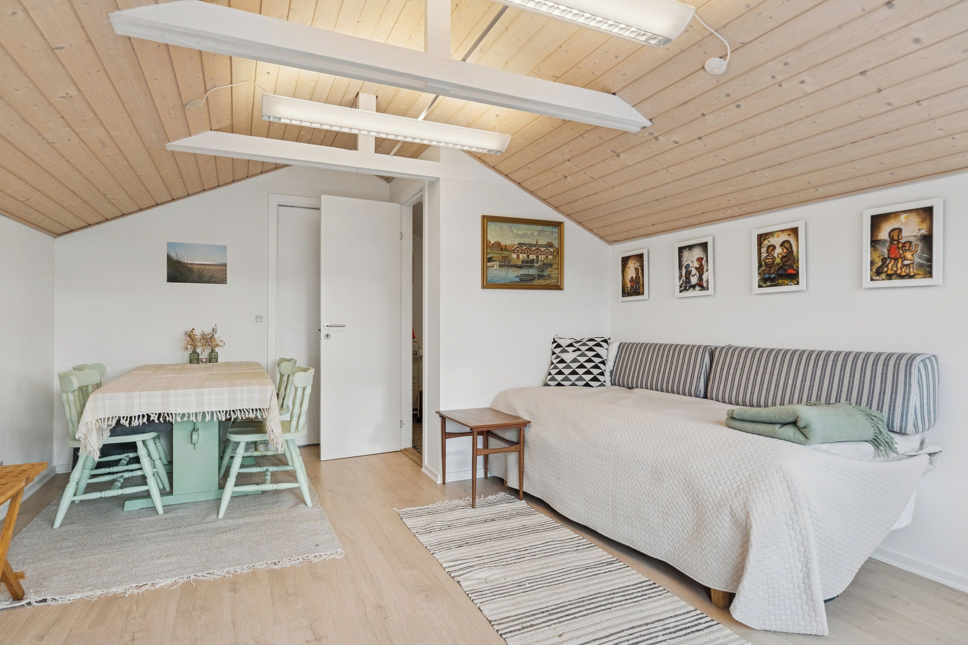 Ein Zimmer mit einem Bett, einem Esstisch und einem Gemälde an der Wand.