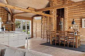 A log cabin interior with a kitchen, dining area, and a sofa. - Lovely log house on Møn (Stege)