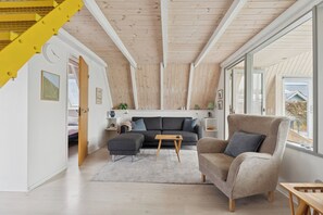 Ein modernes Wohnzimmer mit einer Couch, einem Sessel, einem Hocker und einem Holztisch.