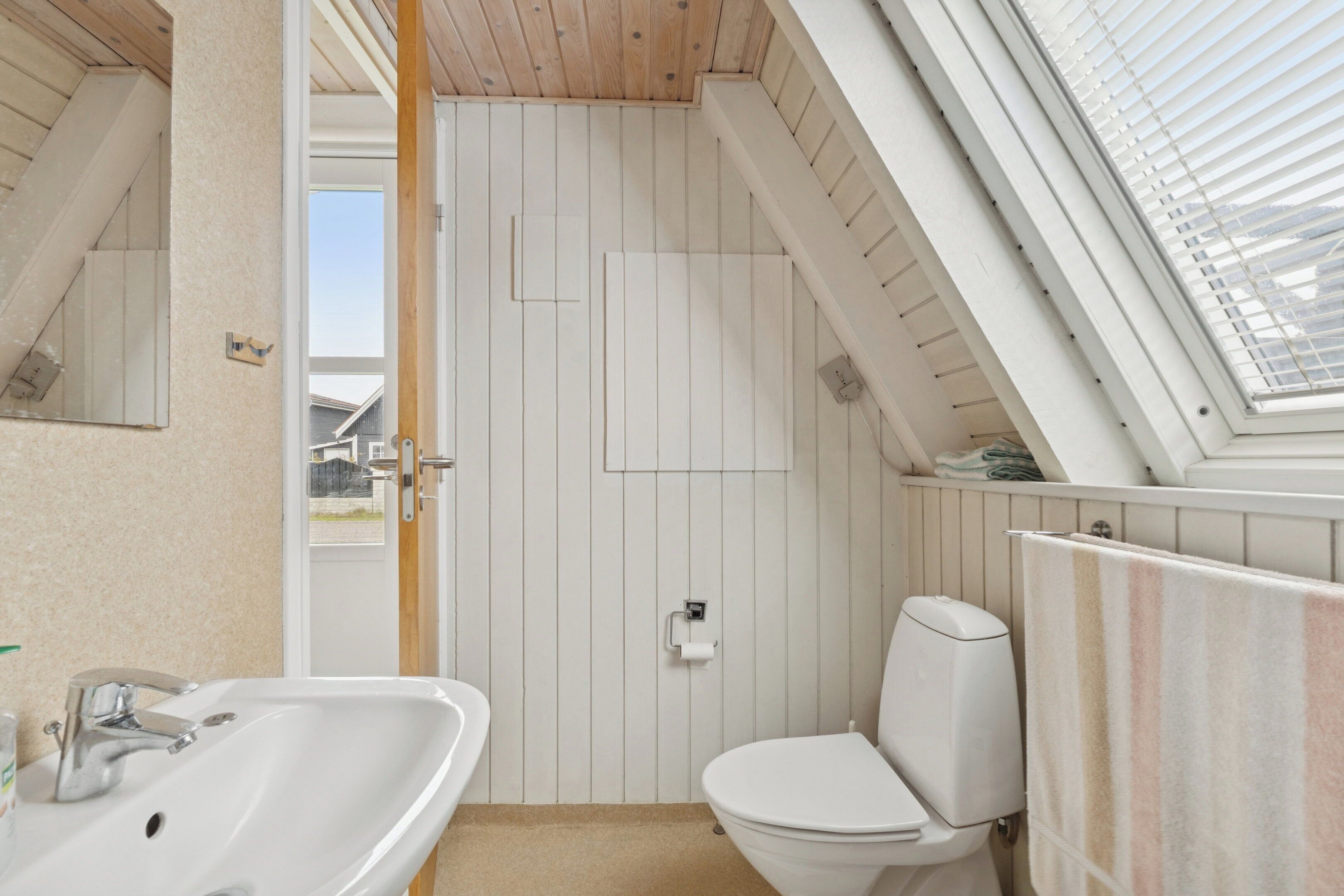 A bathroom with a skylight, a white sink, and a toilet.
